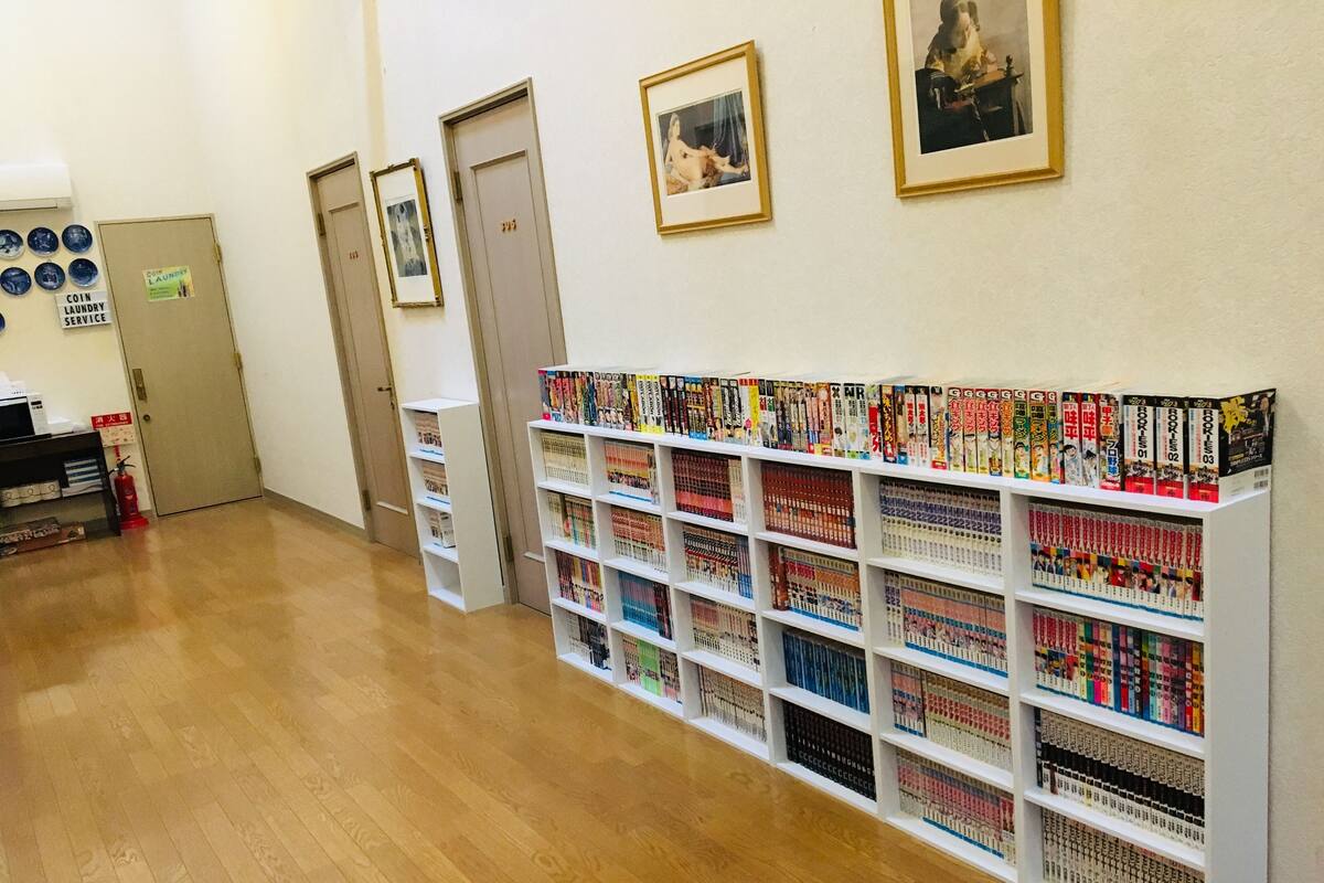 A library with bookshelves filled with books, a fire extinguisher, and a door with a sign indicating coin laundry service.