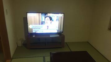 Un televisor sobre un atril de madera en una habitación con suelo de tatami.