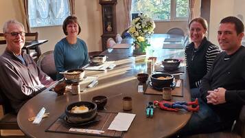 A dining table with bowls of food, a clock, and a vase of flowers.