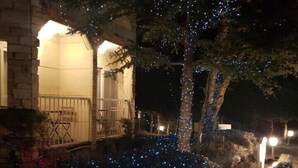A house with a stone facade, a wooden deck, and a tree wrapped in blue lights. - Nikko Ikoi Hotel (Nikko)