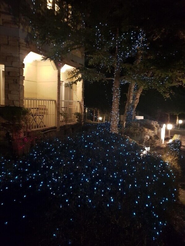 A house with a stone facade, a wooden deck, and a tree wrapped in blue lights. - Nikko Ikoi Hotel (Nikko)