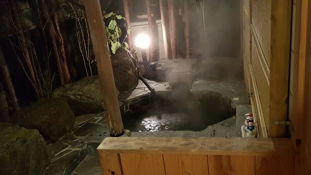 A hot spring area with a wooden bench, stone flooring, and a visible water feature. - Nikko Ikoi Hotel (Nikko)