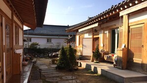 A traditional Japanese-style courtyard with stone lanterns, a small tree, and a wooden gate. - Doran Doran Guesthouse (Gyeongju)