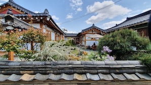A traditional Japanese courtyard with wooden buildings, stone walls, and a variety of plants. - Doran Doran Guesthouse (Gyeongju)
