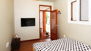 A bedroom with a bed, a TV mounted on the wall, a wooden door, and a window with a lattice design. - Doran Doran Guesthouse (Gyeongju)