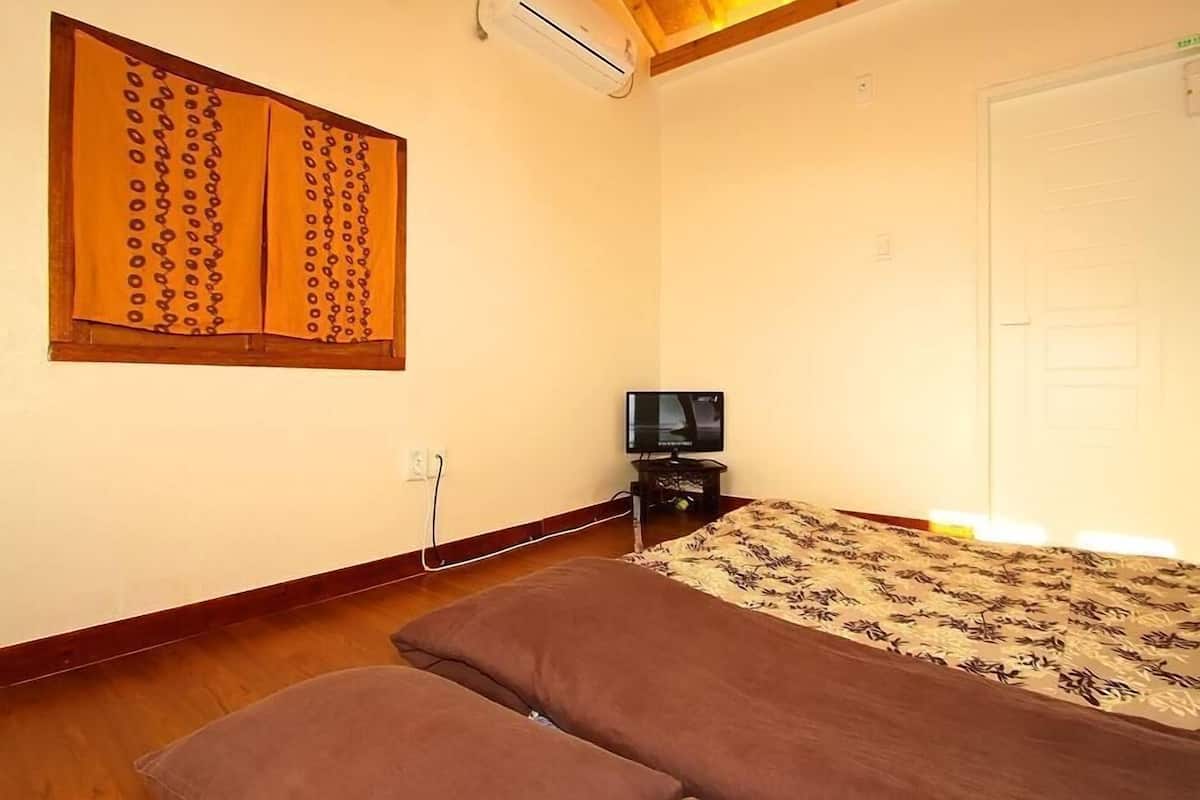 A room with a bed, a television, and a window with curtains.