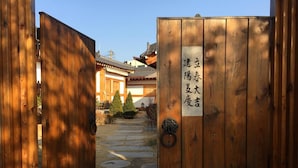 A wooden gate with a sign, leading to a traditional building with a tiled roof and a stone pathway. - Doran Doran Guesthouse (Gyeongju)