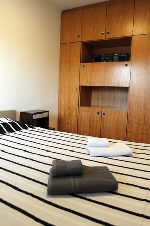 Une chambre d’hôtel avec un lit, une armoire en bois et une petite table de chevet.