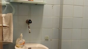 Ein Badezimmer mit einem Standwaschbecken, einem Spiegel darüber und einer Toilette.