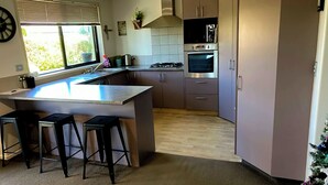 Une cuisine moderne avec un îlot central, des tabourets de bar, une cuisinière, un four et un petit sapin de Noël.