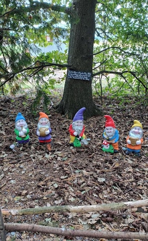 Garden gnomes sitting on a leaf-covered ground with a tree and a sign in the background. - Methven Crash Pad, Methven (Methven)