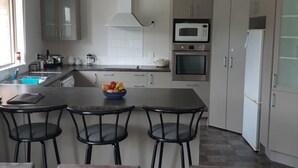 Una cocina moderna con una isla central, microondas, horno y refrigerador.