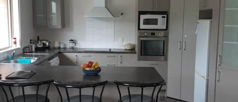 A modern kitchen with a central island, a microwave, oven, and a refrigerator.