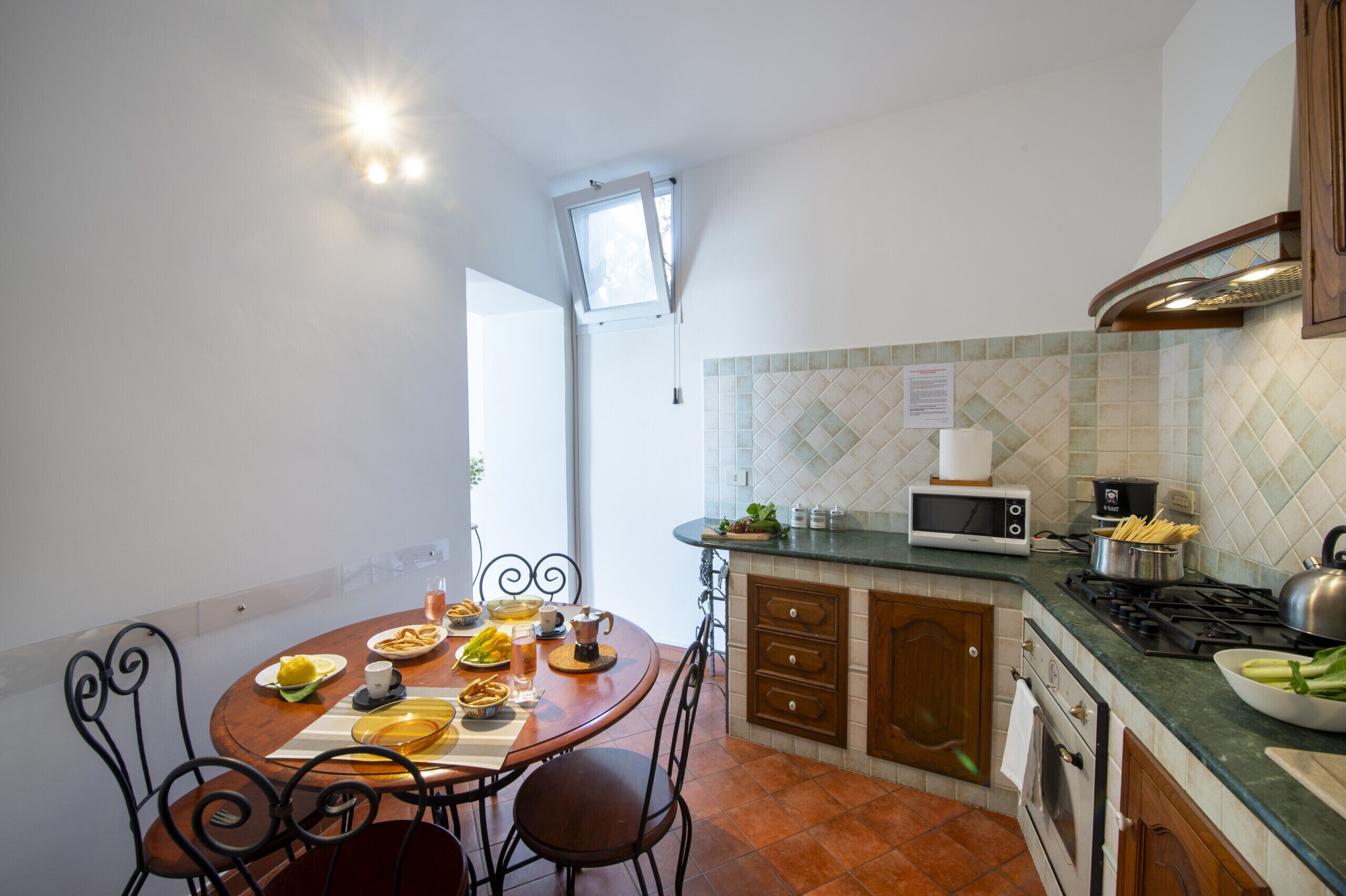 A kitchen with a dining table set for two, a microwave, stove, and cabinets.