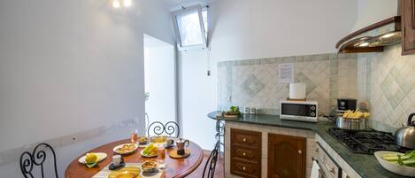 A kitchen with a dining table set for two, a microwave, stove, and cabinets.