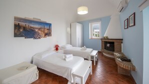 A bedroom with two beds, a fireplace, and a beach painting.