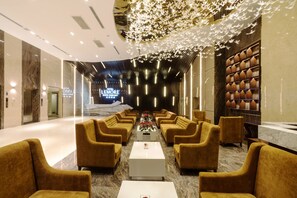 Una hall d'albergo con un'area salotto centrale, una reception e un soffitto decorativo.