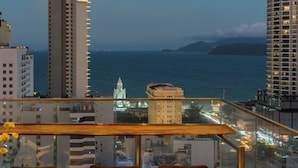 A cityscape with a view of the sea, tall buildings, and a balcony with chairs. - LeMore Hotel Nha Trang (Nha Trang)