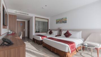 A hotel room with two beds, a desk with a telephone, a small table, and a painting on the wall.