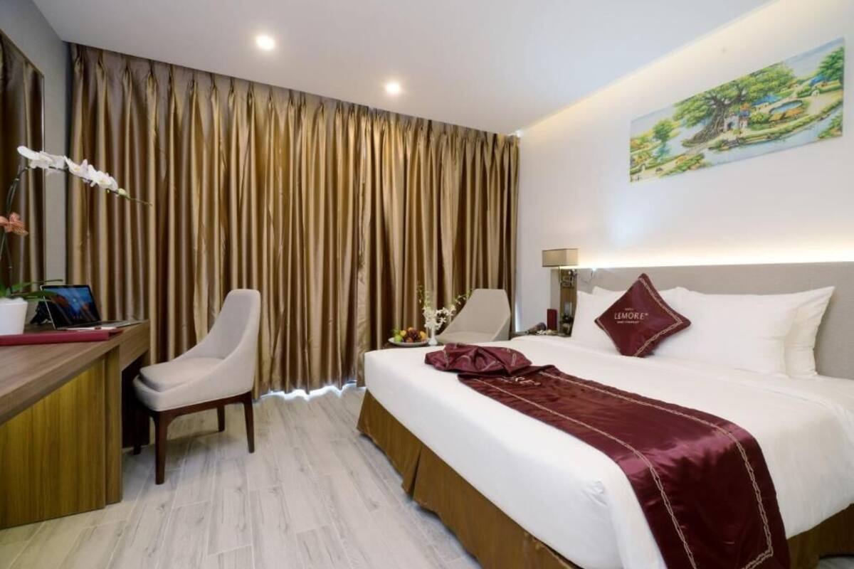 A hotel room with a bed, a desk, a chair, and a nightstand.