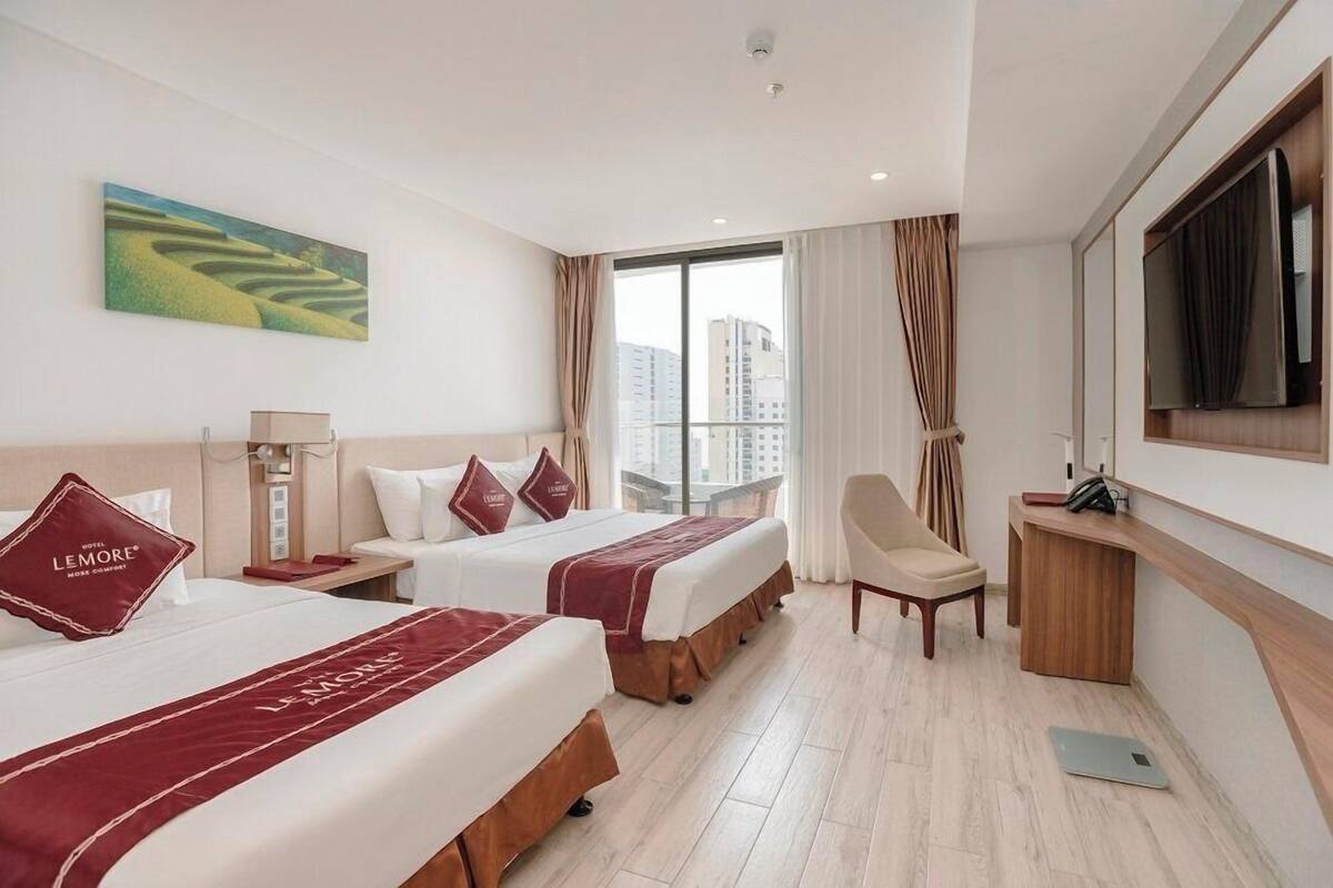 A hotel room with two beds, a desk, a chair, a TV, and a painting on the wall.