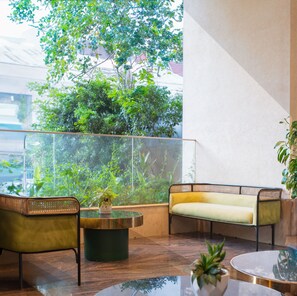 Uma área de estar interna moderna com sofá, cadeiras, uma mesa de vidro e um vaso de planta.