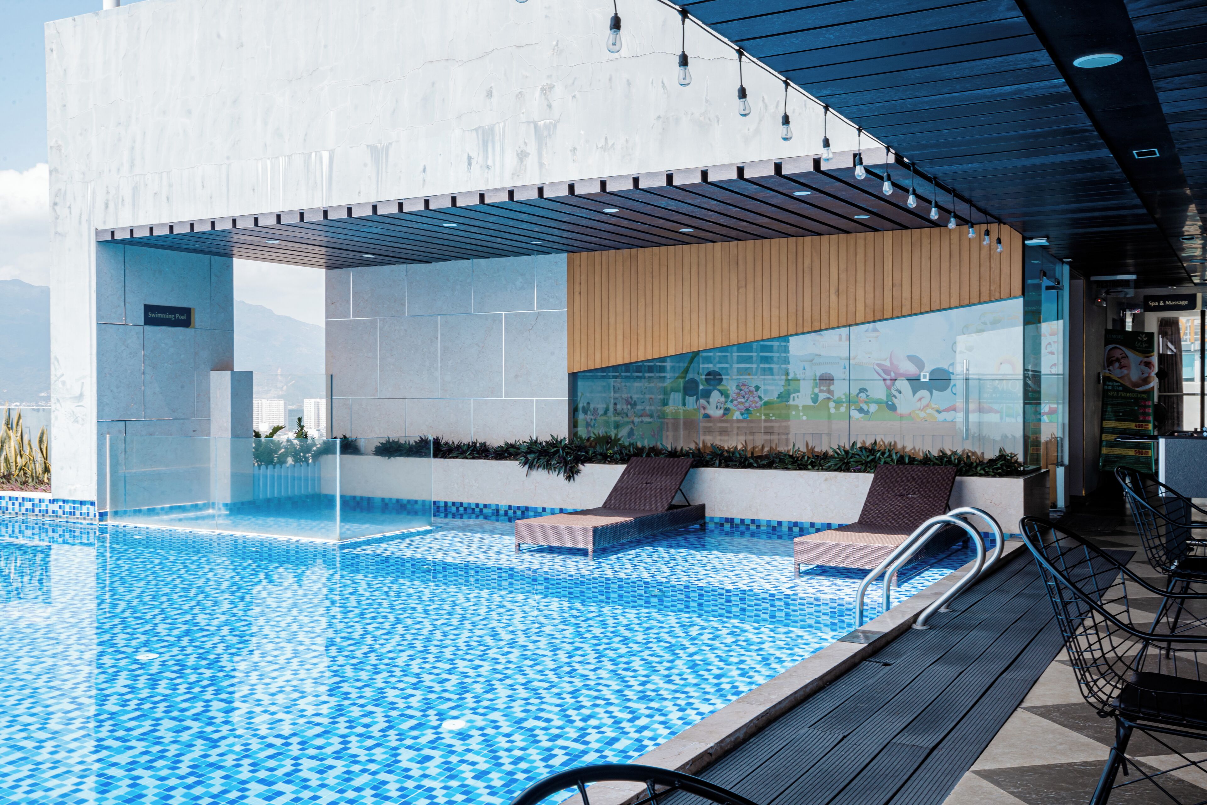 A modern pool area with a clear pool, wooden deck, and lounge chairs.