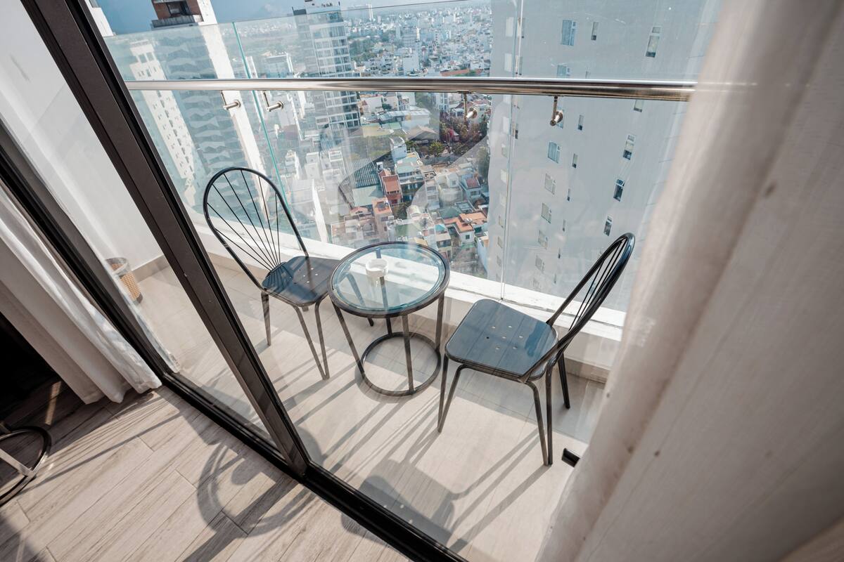 A balcony with two chairs and a table, offering a city view.