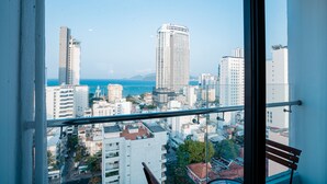 A cityscape view from a balcony with a clear sky, featuring tall buildings and a body of water in the distance. - LeMore Hotel Nha Trang (Nha Trang)