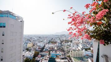 Un paisaje urbano con edificios, cielo despejado y flores rosadas en primer plano.
