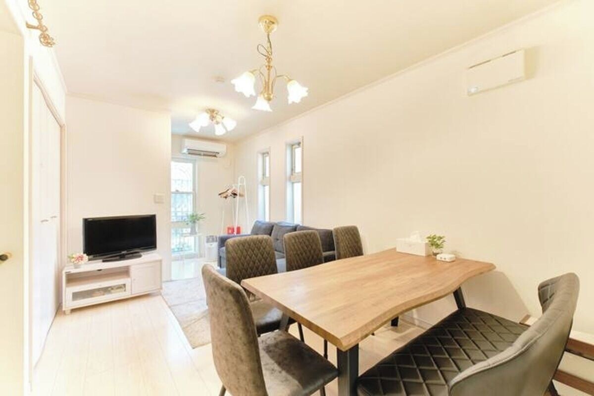 A modern living room with a dining area, a flat-screen TV, and a sofa.