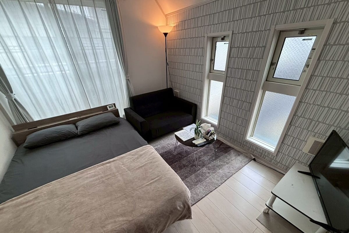 Una habitación moderna y funcional con cama, sofá, escritorio y televisor.