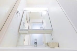 A bathroom with a white bathtub, a mirror, and a towel rack. - Soshigaya Apartment (Tokyo)