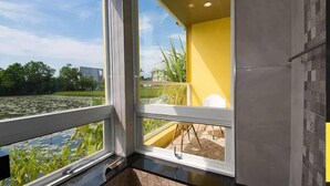 A room with a large window overlooking a pond and greenery. - Tourist Home B&B (Luodong)