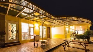 A covered outdoor seating area with wooden flooring, a picnic table, and a glass railing. - Tourist Home B&B (Luodong)