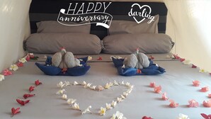 A bed with two plush toys resembling turkeys, a heart-shaped flower arrangement, and text indicating a 'HAPPY anniversary'. - Ings Garden (Gili Air)