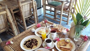 A dining table with breakfast items including toast, pancakes, and a drink. - Ings Garden (Gili Air)