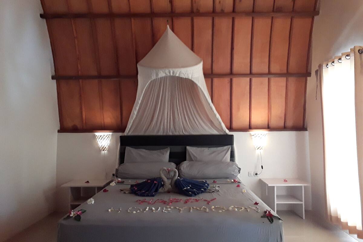 A bed with a canopy, two bedside tables, and a wall-mounted lamp.