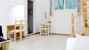 A spacious room with a wooden ceiling, a white sofa, a desk with a computer, a chair, and a staircase. - Namubyeol (Gapyeong)