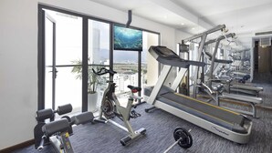 Un gimnasio con equipo de cardio, máquinas de pesas y una cinta de correr.