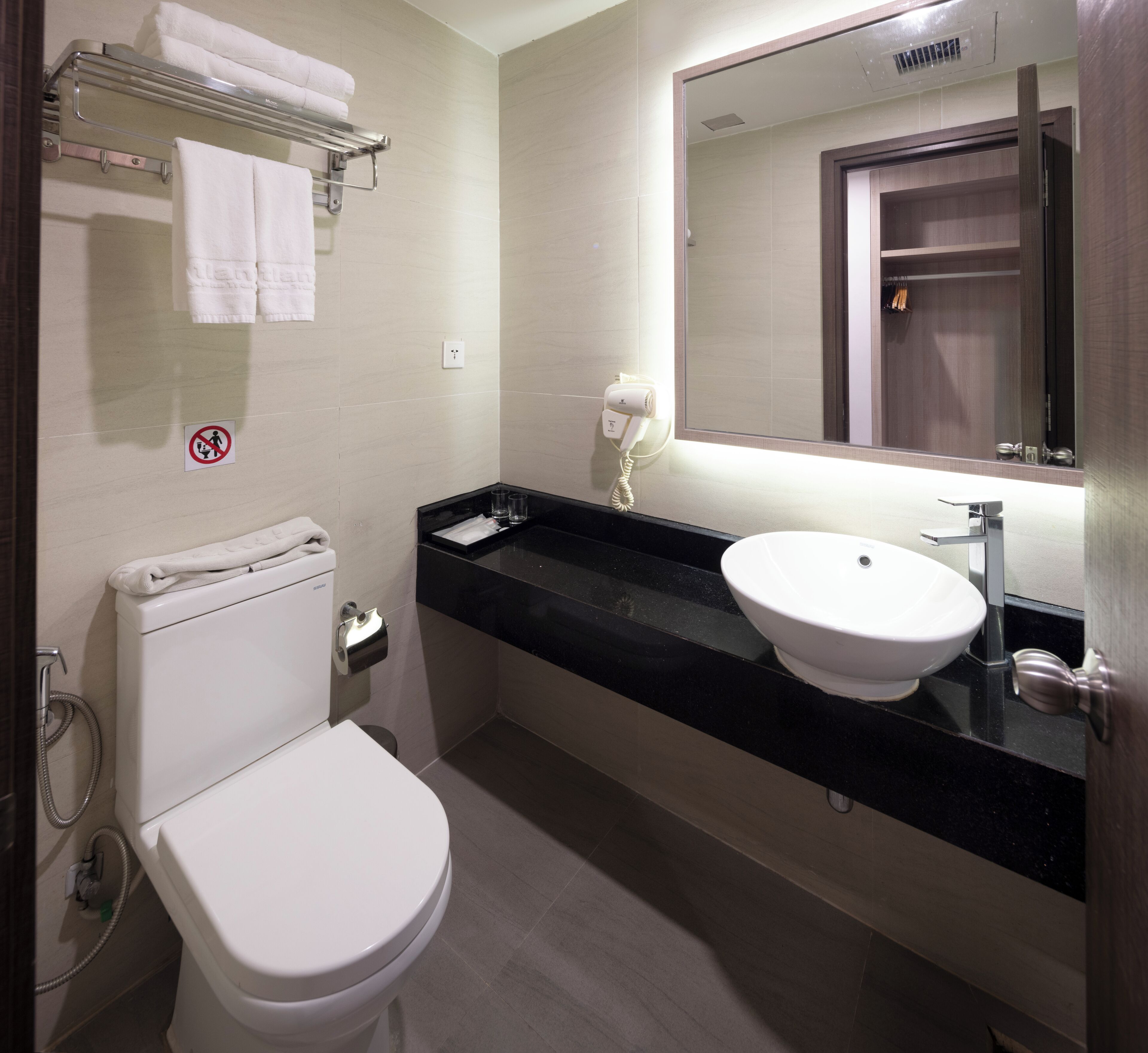 Une salle de bain moderne équipée de toilettes, d’un lavabo et d’un porte-serviettes.