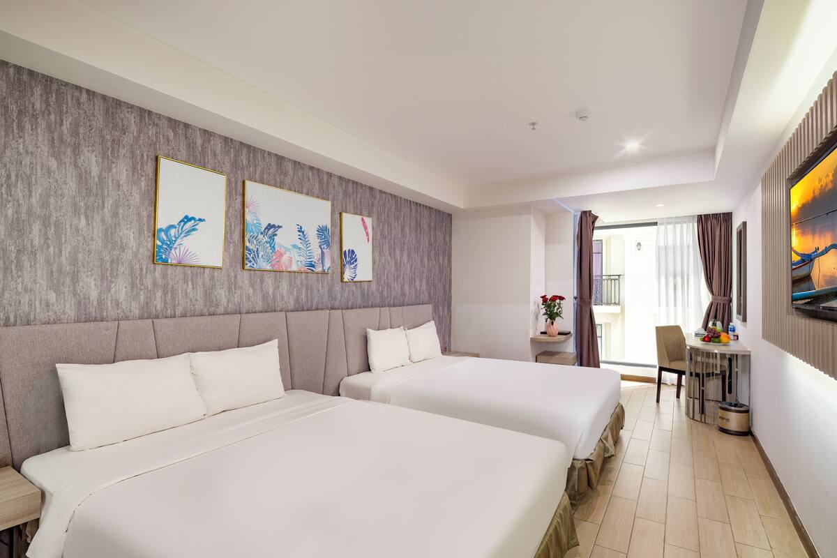 Une chambre d’hôtel avec deux lits, un coin repas et des œuvres d’art accrochées au mur.