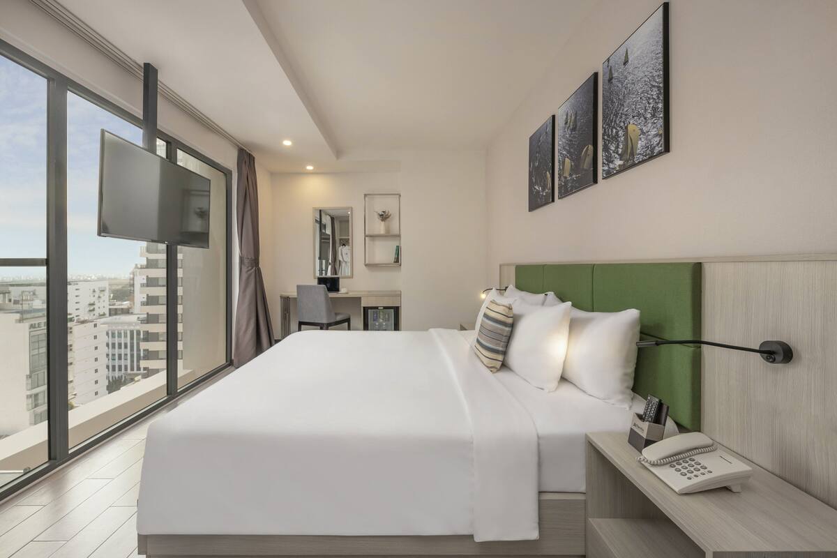 Une chambre d’hôtel moderne, dotée d’un grand lit, d’un bureau et offrant une vue sur la ville.