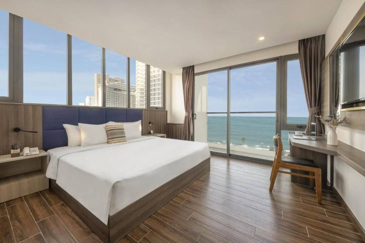 Une chambre d’hôtel moderne avec un grand lit, un bureau et une vue sur l’océan.