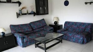 Una sala de estar con un conjunto de sofá, una mesa de centro de vidrio y un mueble negro.