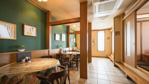 A restaurant with a large round table, wooden chairs, and framed pictures on the walls. - Pacific Hotel Shiroishi (Shiroishi)