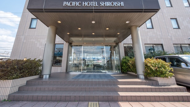 The entrance to Pacific Hotel Shiroishi with a modern design, featuring a covered entrance, glass doors, and a brick pathway leading up to the entrance. - Pacific Hotel Shiroishi (Shiroishi)