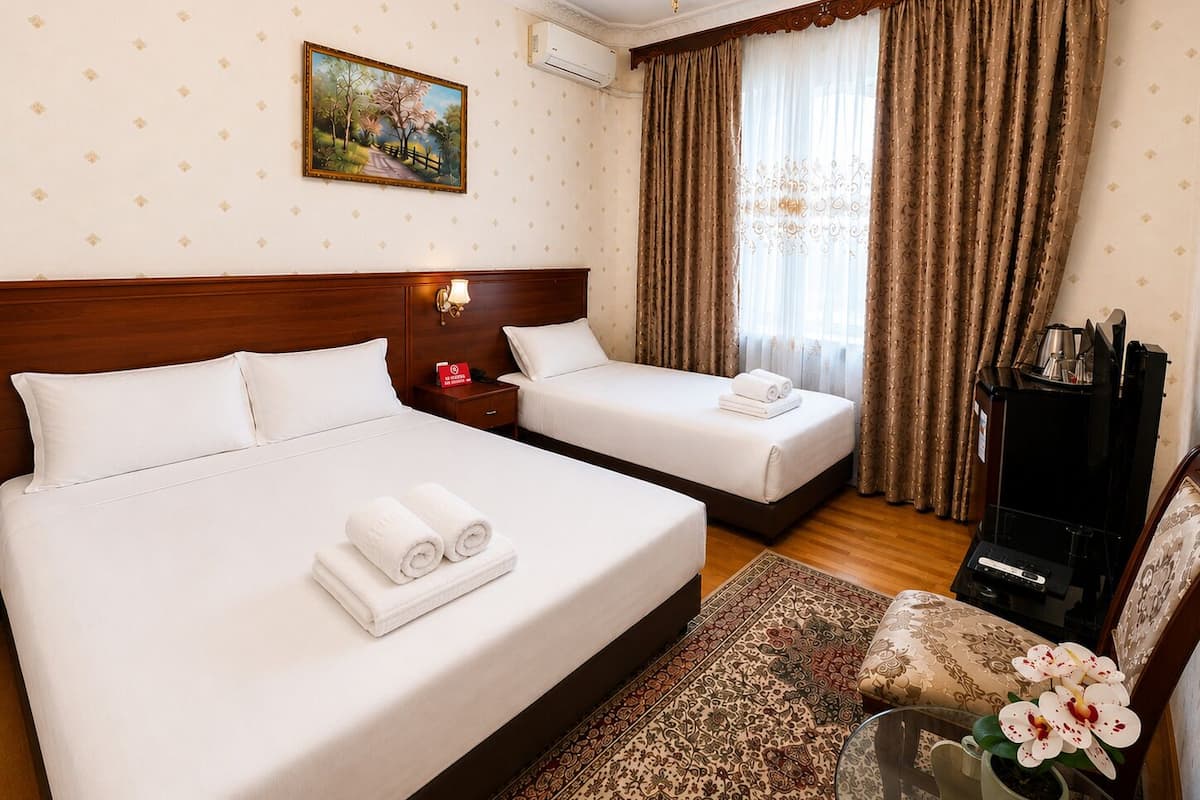 A hotel room with two beds, a painting on the wall, a chandelier, a coffee machine, and a floral arrangement.
