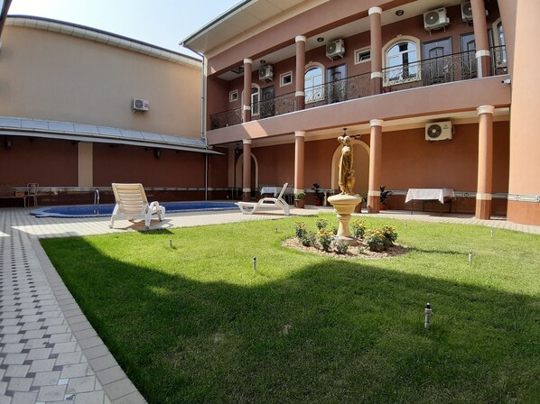 A courtyard with a swimming pool, lounge chairs, a fountain, and a covered seating area. - Sarbon Hotel (Tashkent)