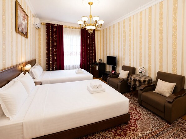 Una habitación de hotel con dos camas, un sofá, un televisor y una mesita con un florero.